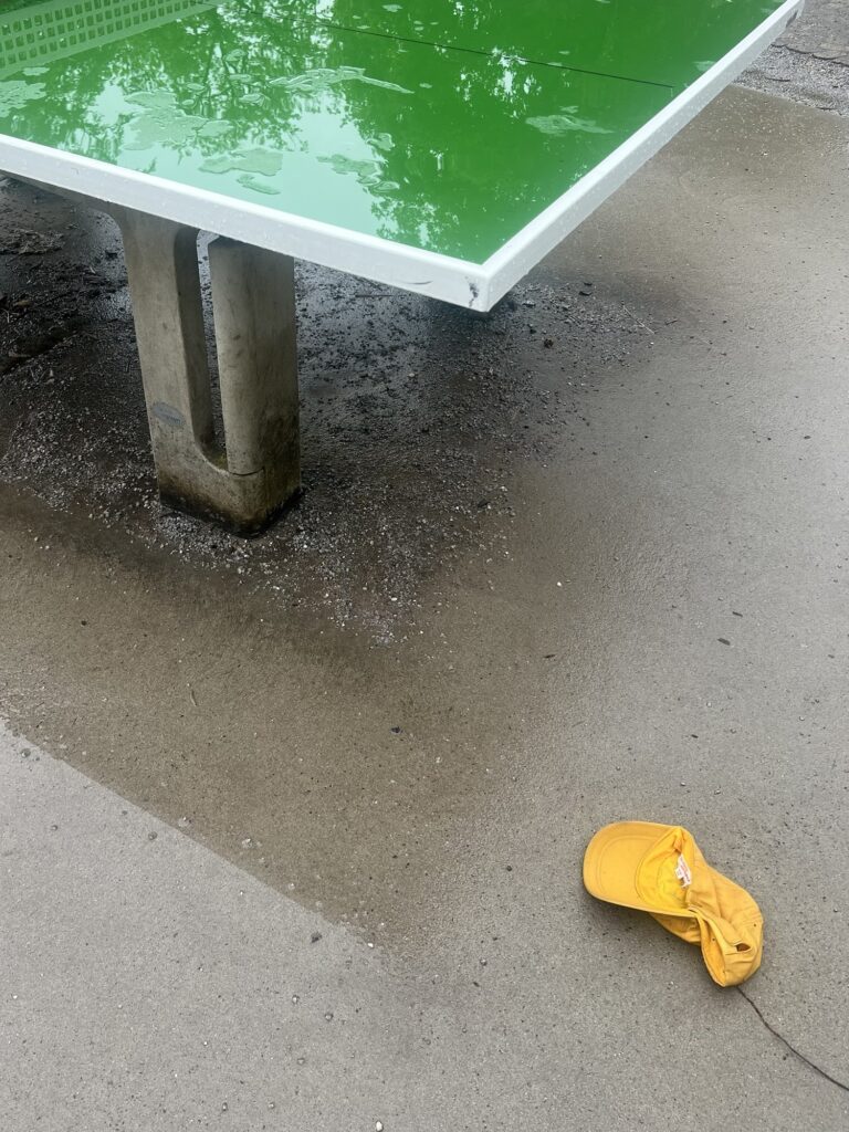 Nass spiegelnde Tischtennisplatte und einsame Mütze