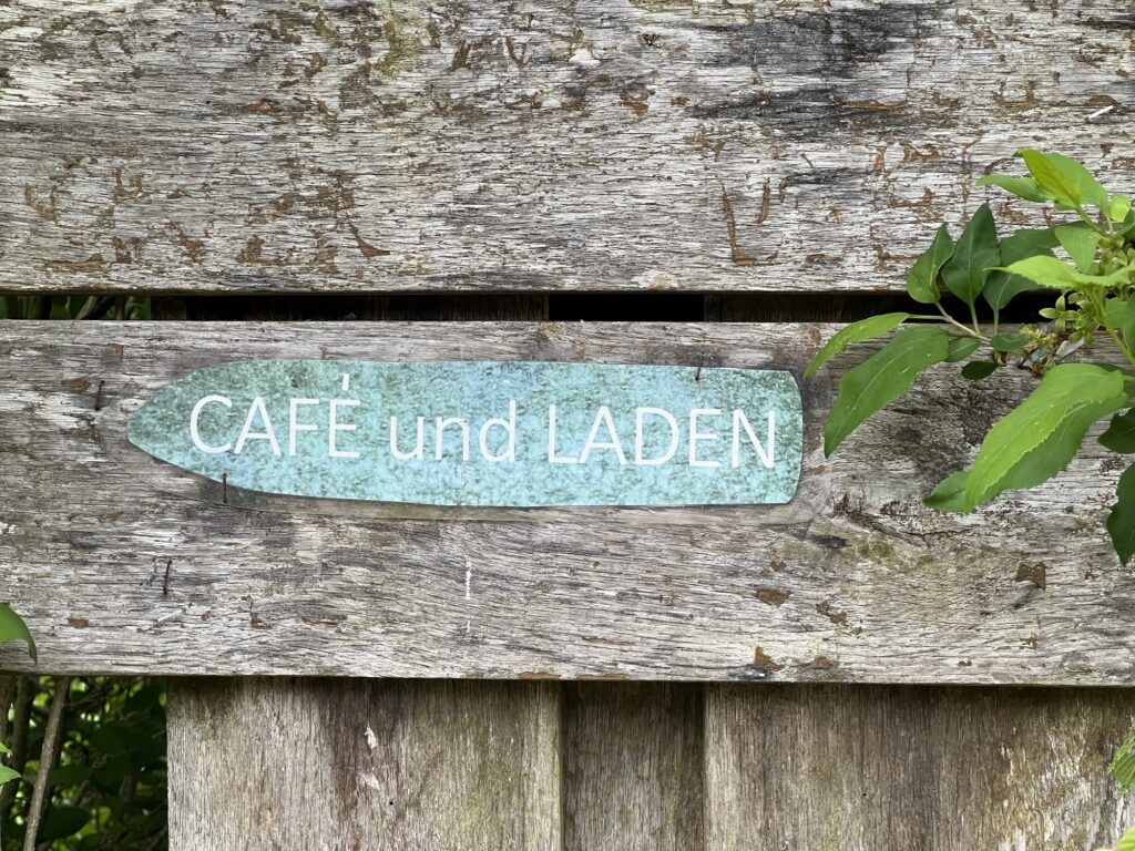 Ramponierter Wegweiser zum Café und Laden