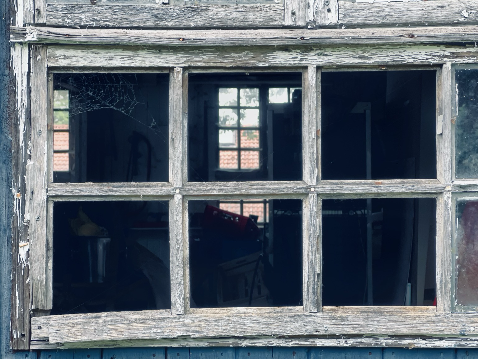 Schuppenfenster mit fehlenden Glasscheiben und Sicht auf beziehungsweise durch gegenüberliegendes Fenster