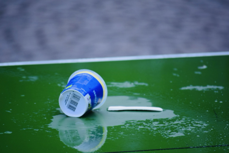 Löffel und umgekippter Becher (Müll) auf Tischtennisplatte