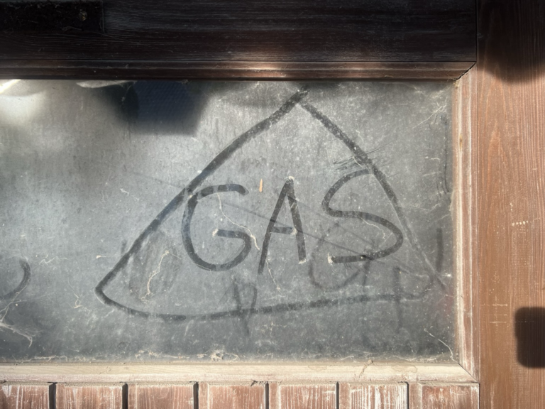 Dreckiges Schuppenfenster mit Dreieck und Buchstaben GAS